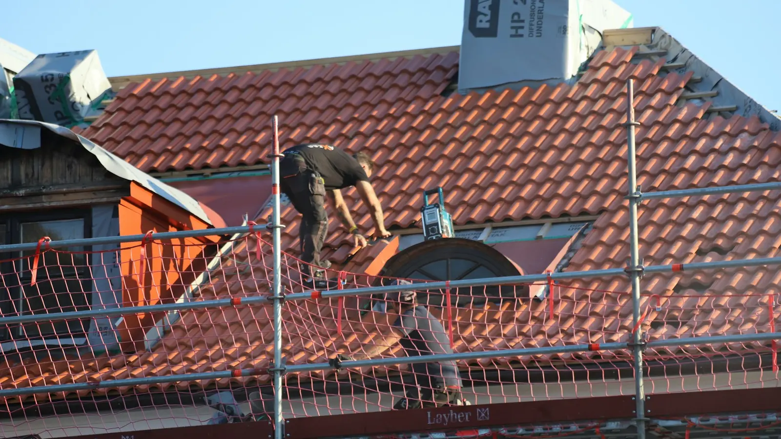 Worker examining a roof from secured access equipment